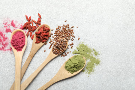 Different superfood powders in spoons on light grey table, flat layの写真素材