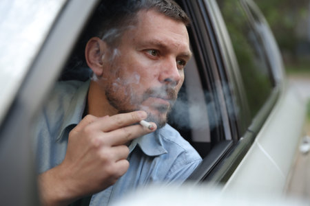 Man smoking cigarette in car, view from outsideの写真素材