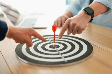 Men pointing at dartboard at wooden table indoors, closeupの写真素材