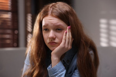 Sad teenage girl on sofa at homeの写真素材