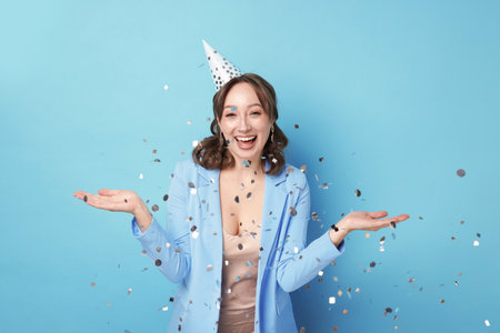 Birthday celebration. Woman on light blue background with confettiの写真素材