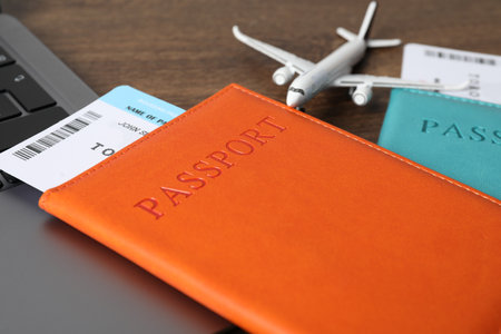 Passports, flight tickets, plane model and laptop on wooden table, closeupの写真素材