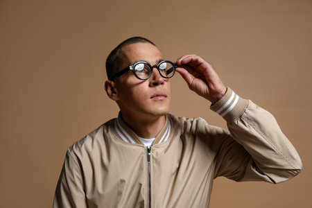 Fashionable portrait of handsome man in stylish outfit on brown backgroundの写真素材