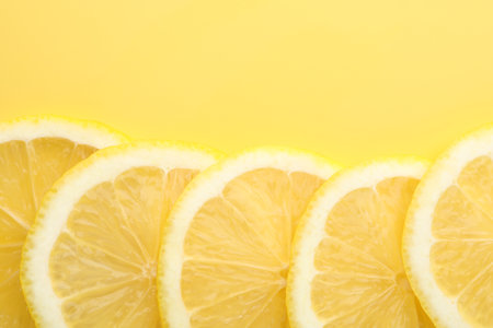 Slices of fresh lemons on yellow background, flat lay. Space for textの写真素材