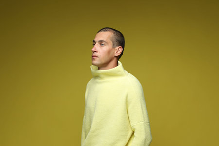 Fashionable portrait of handsome man in stylish outfit on olive background