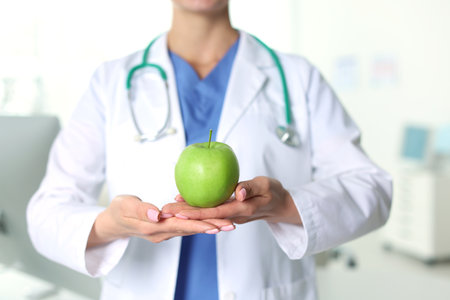 Nutritionist with green apple and stethoscope in clinic, closeupの写真素材