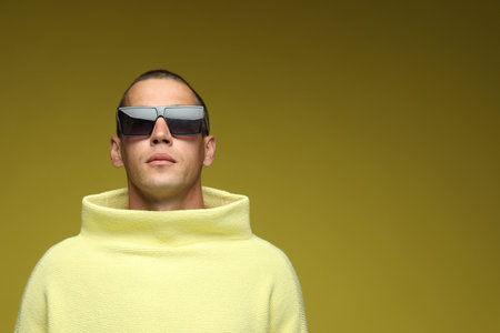 Fashionable portrait of handsome man in stylish outfit on olive background, space for textの写真素材