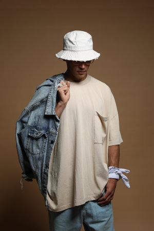 Fashionable portrait of handsome man in stylish outfit on brown backgroundの写真素材