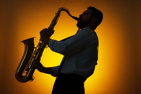 Professional musician playing saxophone on color background, backlitの写真素材