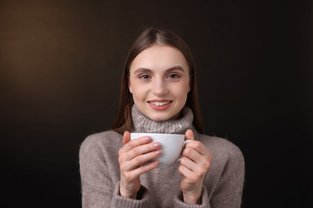 Smiling woman with cup of coffee on brown gradient backgroundの写真素材
