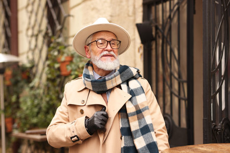 Stylish senior man with hat and scarf in outdoor barの写真素材