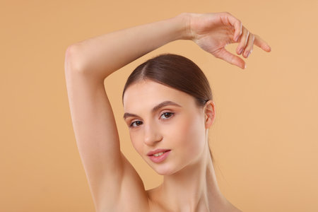 Young woman showing smooth skin after epilation on beige backgroundの写真素材