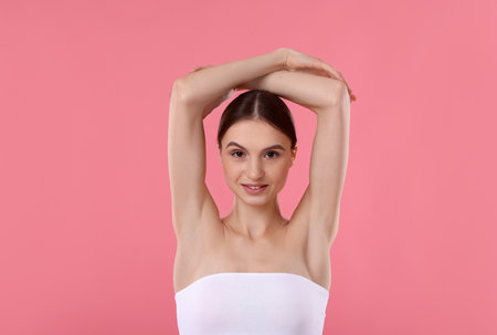 Young woman showing smooth skin after epilation on pink backgroundの写真素材