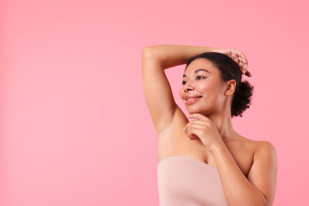 Woman showing hairless armpit after epilation procedure on pink background, space for textの写真素材