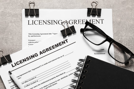 Licensing agreement documents, notebook, glasses and pen on gray textured table, flat lay