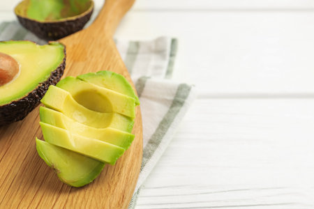 Tasty cut avocados on white wooden table, closeup. Space for textの写真素材