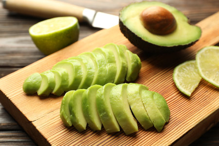 Cut ripe green avocado and lime on wooden table, closeupの写真素材