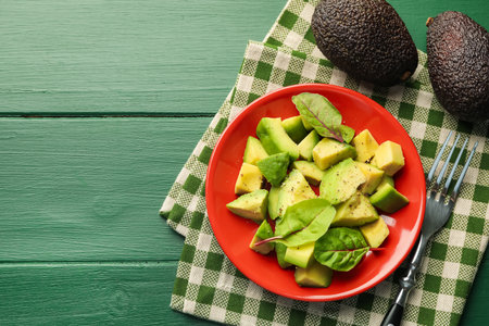 Tasty cut avocados with spinach and dressing on green wooden table, flat lay. Space for textの写真素材