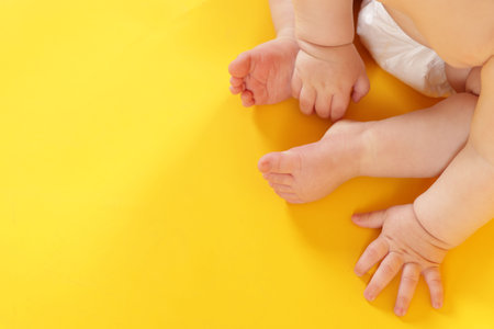 Cute little baby in diaper on yellow background, above view. Space for textの写真素材