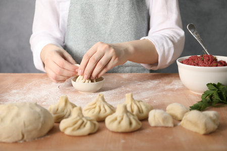 Woman making khinkali on table in kitchen, closeupの写真素材