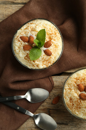 Delicious rice pudding with cinnamon, almonds and mint served on wooden table, flat layの写真素材