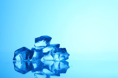 Cubes of clear ice on light blue background, closeup. Space for textの写真素材