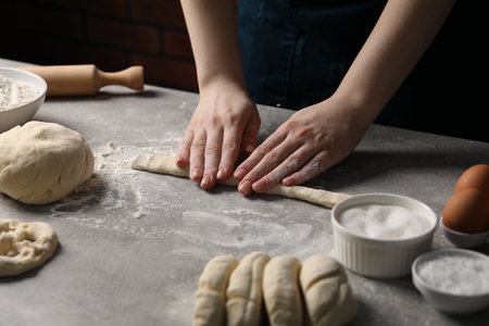 Woman making pretzel at light grey table, closeupの写真素材