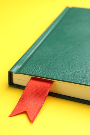 Book with red ribbon bookmark on yellow background, closeupの写真素材