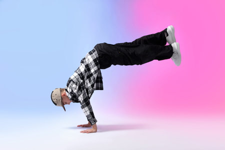 Boy in stylish clothes dancing on color background