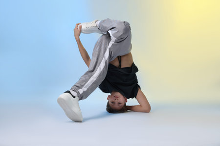 Boy in stylish clothes dancing on color background