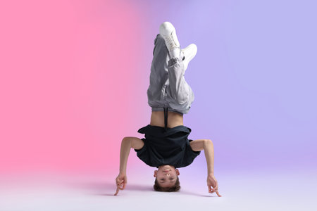 Boy in stylish clothes dancing on color background