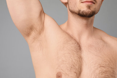 Young man showing hairy armpit on light grey background, closeup. Epilation procedureの写真素材