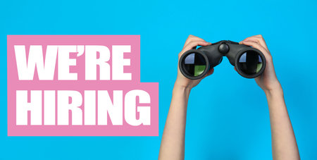 Woman with binoculars on light blue background, closeup.の写真素材