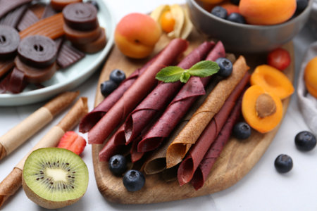 Tasty candied leather rolls, fruits and berries on white table, closeupの写真素材