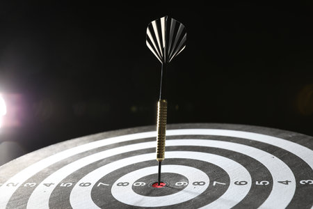 Targeting. Dart board with arrow on dark background, closeupの写真素材