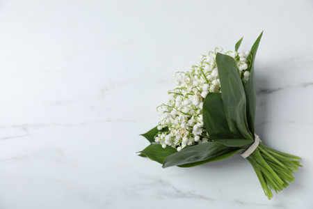 Bouquet of beautiful lily-of-the-valley flowers on white marble background, top view. Space for textの写真素材