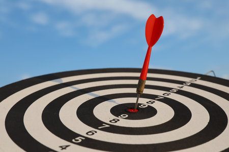 Targeting. Dart board with arrow against blue sky, closeupの写真素材