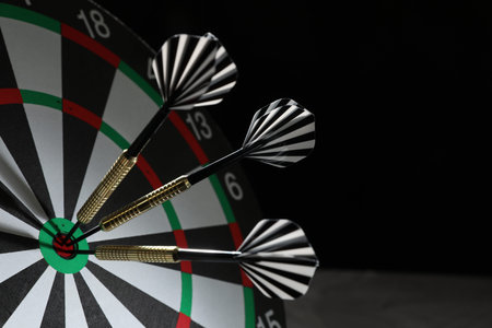 Targeting. Dart board with arrows on black background, closeup