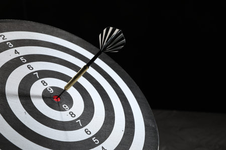Targeting. Dart board with arrow on dark background, closeupの写真素材