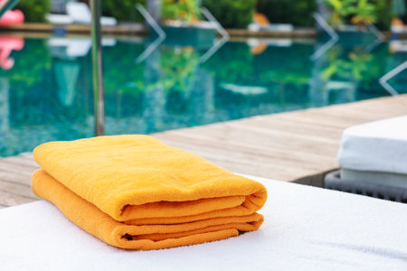 Beach towels on sun lounger near outdoor swimming pool, space for text. Luxury resortの写真素材