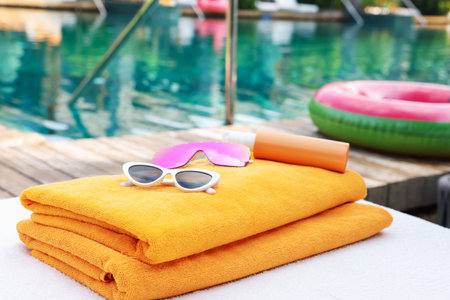 Beach towels and sunglasses on sun lounger near outdoor swimming pool. Luxury resortの写真素材