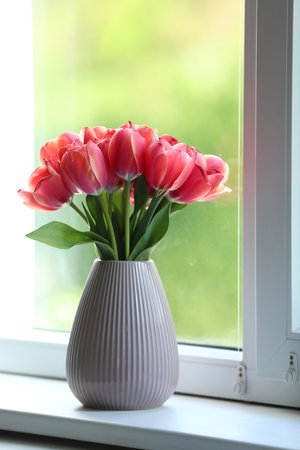 Beautiful tulips in vase on window sillの写真素材