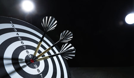 Targeting. Dart board with arrows on dark background, closeup. Space for textの写真素材