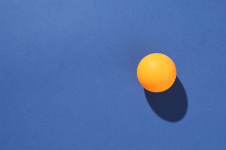 One ping pong ball on blue background, top view. Space for textの写真素材
