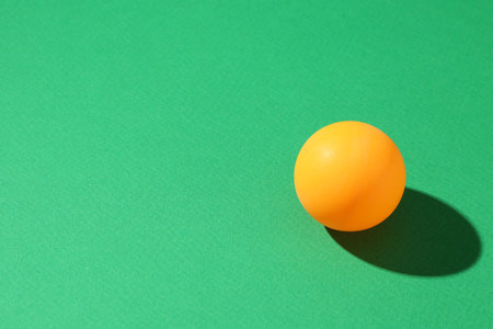 One ping pong ball on green background, closeup. Space for textの写真素材