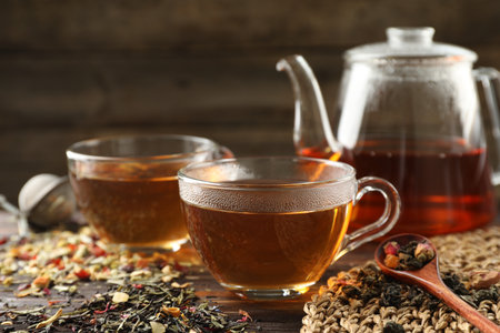 Refreshing herbal tea and dry leaves on wooden table, closeup. Space for textの写真素材