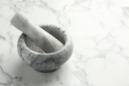 Mortar and pestle on white marble table, closeup. Space for textの写真素材