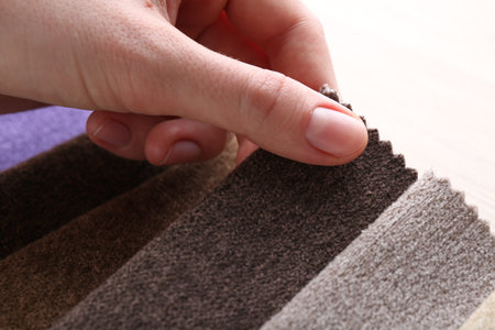 Woman with samples of different fabrics at table, closeup