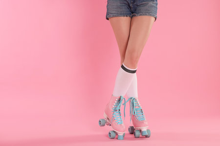 Woman in roller skates on pink background, closeup. Space for textの写真素材