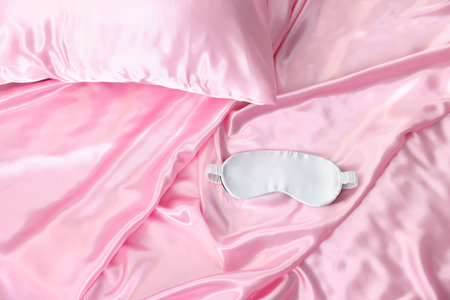 Luxury pink silk linens and sleep mask on bed, top viewの写真素材
